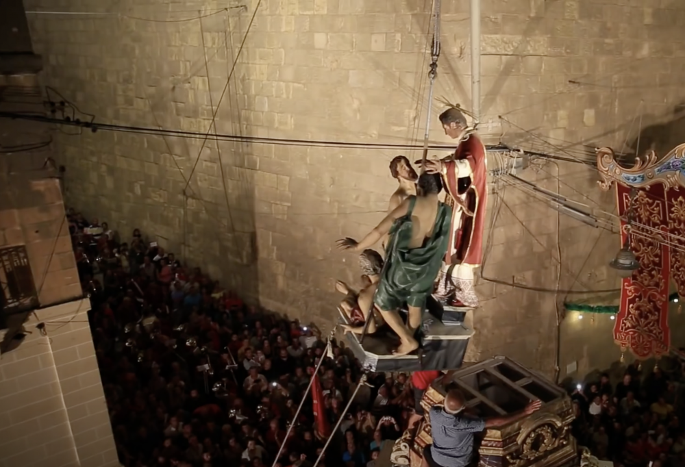 L-istatwa ta’ San Lawrenz jagħti d-dawl lill-għomja titella’ fuq il-kolonna permezz tal-boma 