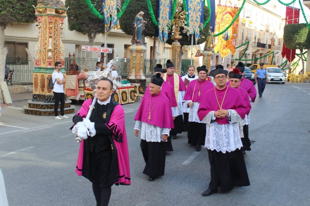 Il-mazzier miexi bil-mazza fuq spalltu quddiem il-Kapitlu Senglean