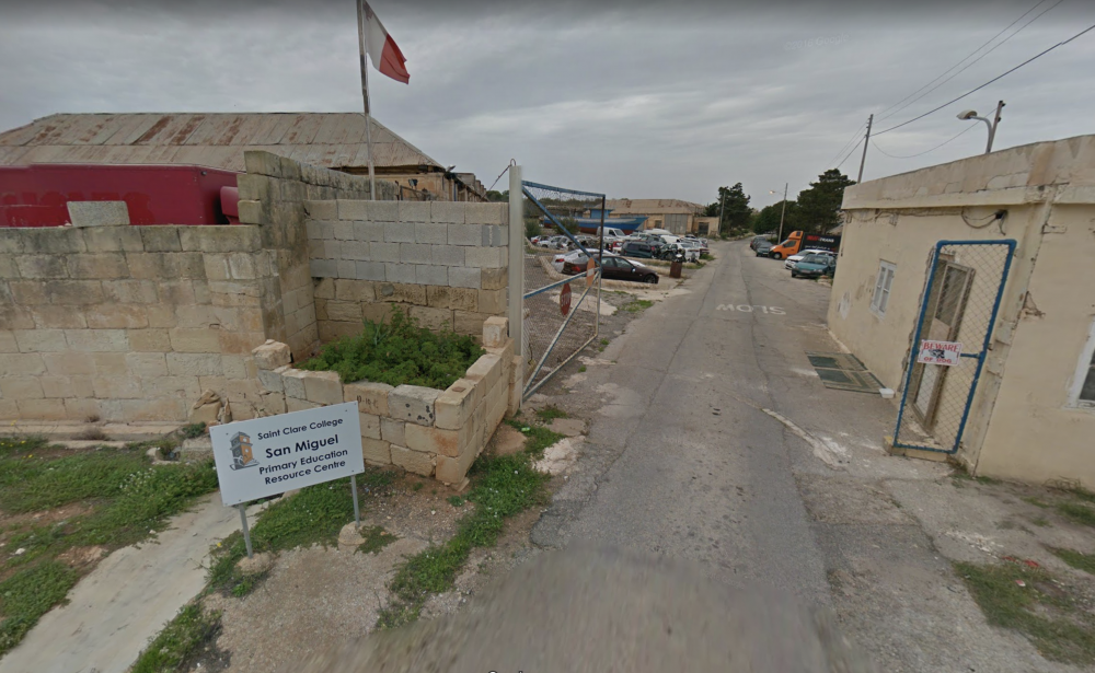 It-tabella taċ-Ċentru San Miguel tindika li l-uniku aċċess għall-iskola huwa l-iscrapyard