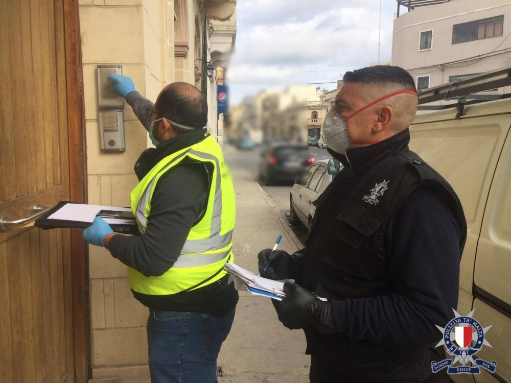 Uffiċjali jikkontrollaw persuni li jinsabu fi kwarantina
