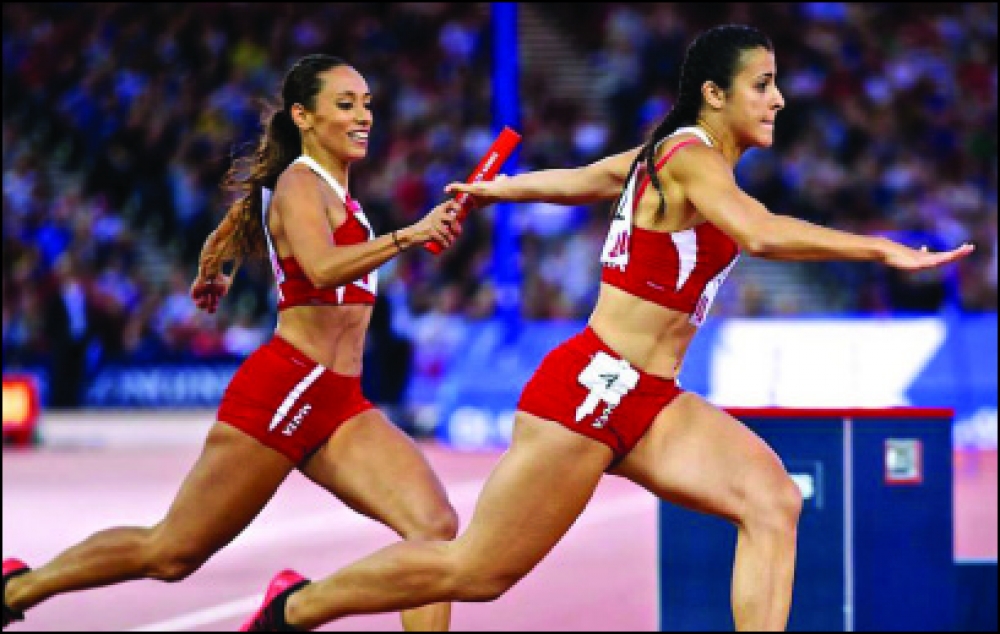 Rachel Fitz tidher tieħu l-baton tar-relay minn id Rebecca Sare’ waqt il-Logħob tal-Commonwealth