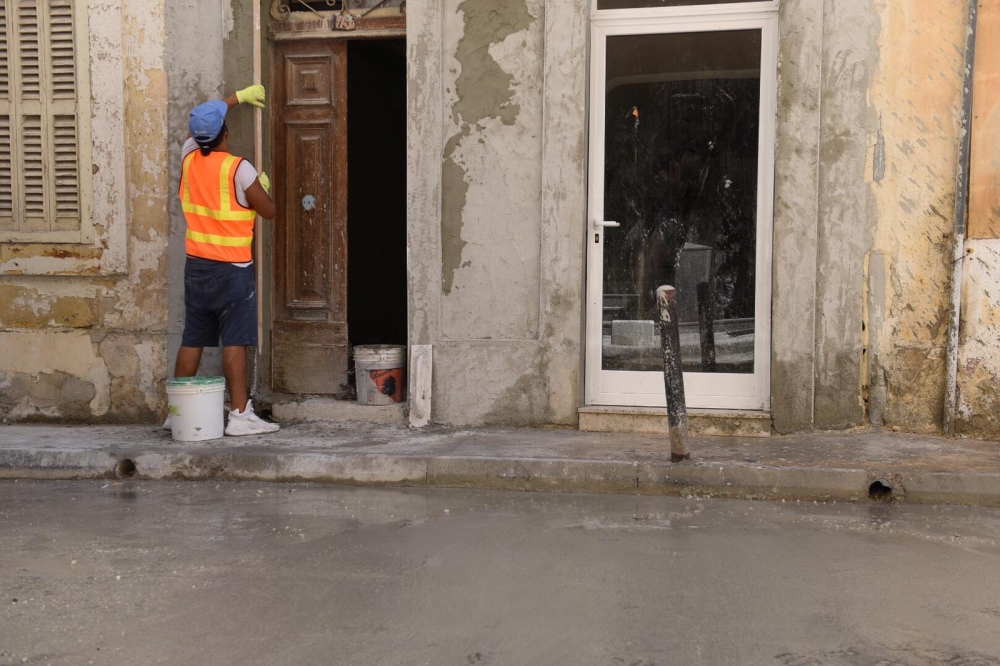 Ħaddiema jnaddfu l-faċċati ta' djar li ntlew bis-siment | Ritratt ta' Zak Camilleri