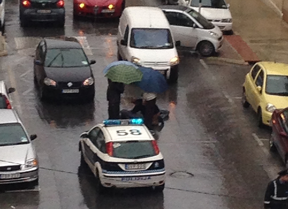Pulizija u persuni oħrajn qrib l-anzjana jistennew l-ambulanza.